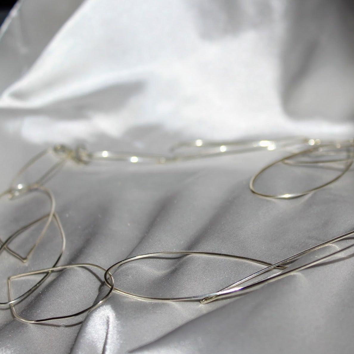 sterling silver handmade Cascade necklace. Each teardrop shaped loop is handmade on a grey silk background
