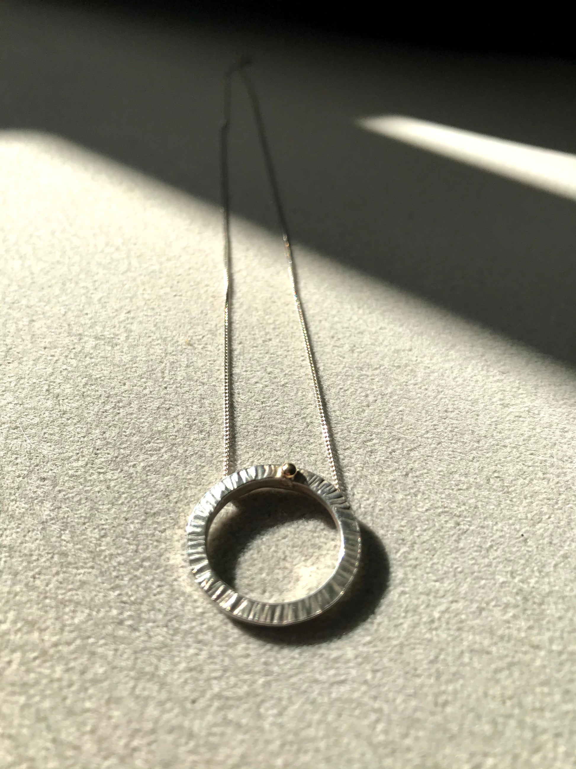 Handmade sterling silver 16mm diameter circle - hammered finish to represent rays of the sun hence the name 'Rise' - this little pendant is suspended on a sterling silver diamond cut curb chain 40cm or 45cm length. The  piece is complete with a ball of 9ct gold so you can Rise with gold.