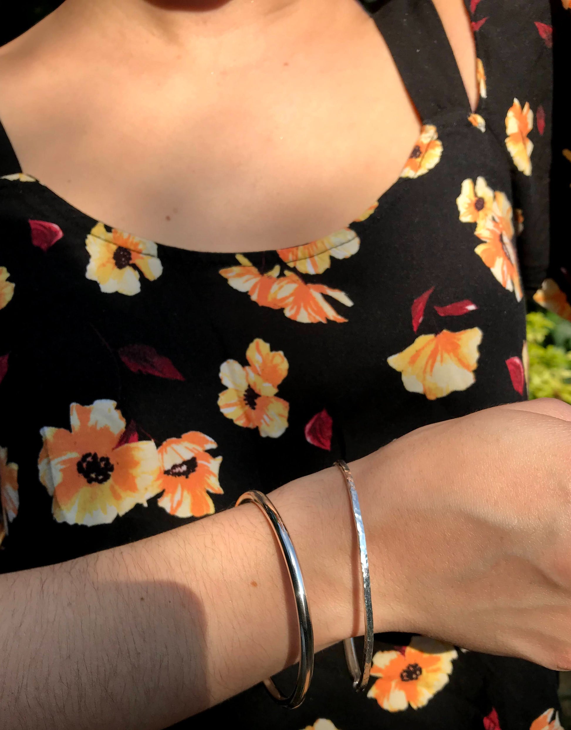handmade sterling silver bangles Polly and Anna pictured on model wearing a black top with orange and yellow flowers