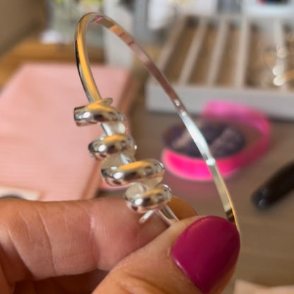 sterling silver handmade bangle is made from D profile silver to give a comfortable fit. The piece itself is a horizontal piece of D profile silver, wound like a coil and stretched out to 4cm and the bangle is threaded trough the piece - it looks and represents a tumbling wave