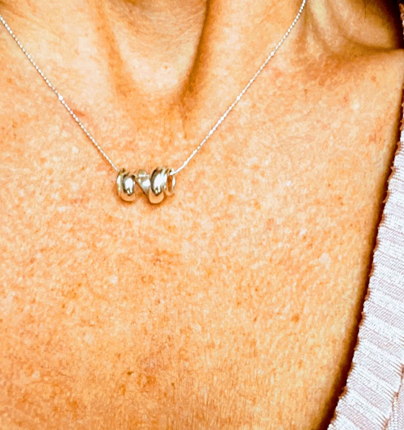 the model is wearing a rolling wave pendant necklace - the piece sits horizontally representing a rolling wave.  The wave rolls and moves on the sparkly ball chain