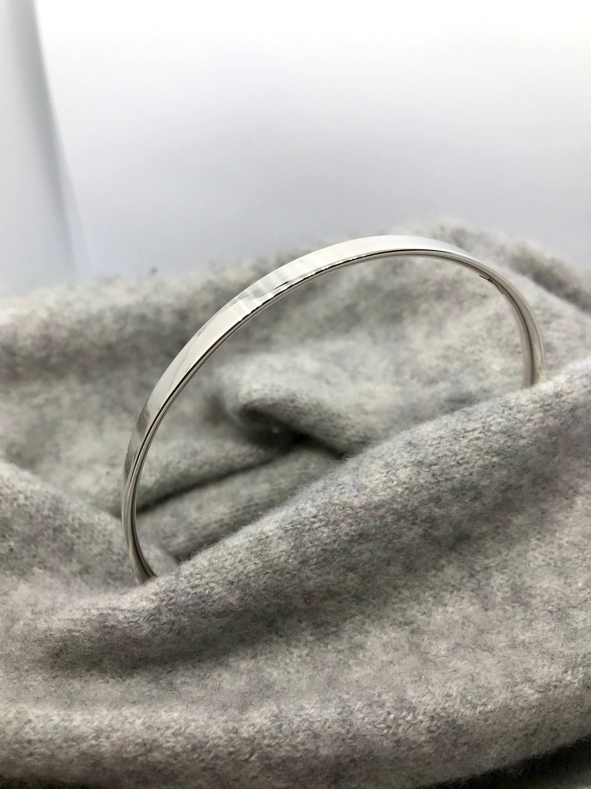Plain and simple Suzanne bangle on a grey cashmere background - handmade in Dublin