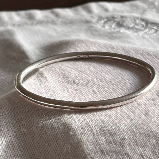 solid sterling silver bangle on a grey linen background