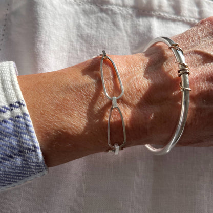 handmade sterling silver solid bangle with 9ct gold wrap of wire twisted around the front of the bangle