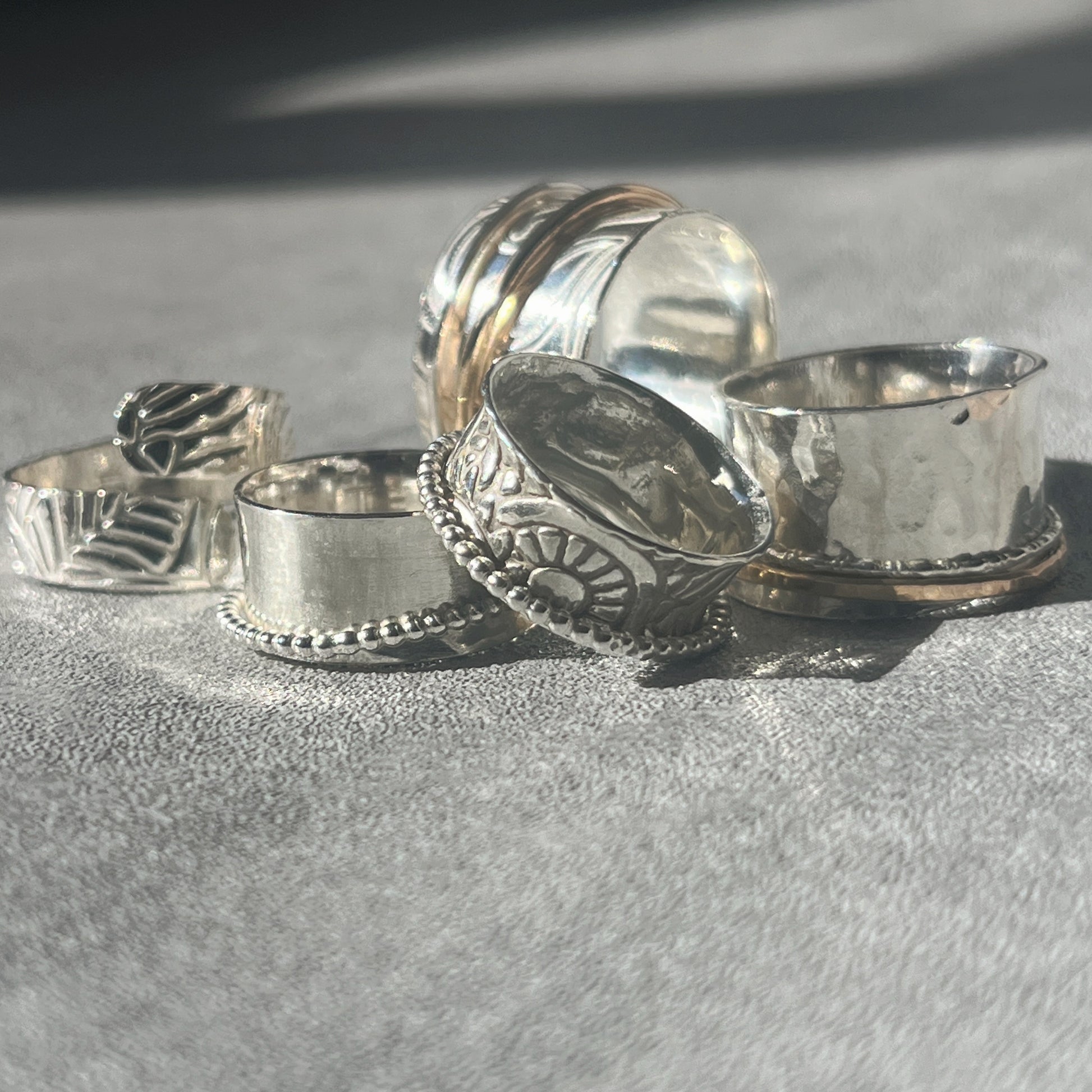 a collection of five various spinner rings some with gold filled outer rings some with silver outer spinner rings all patterned
