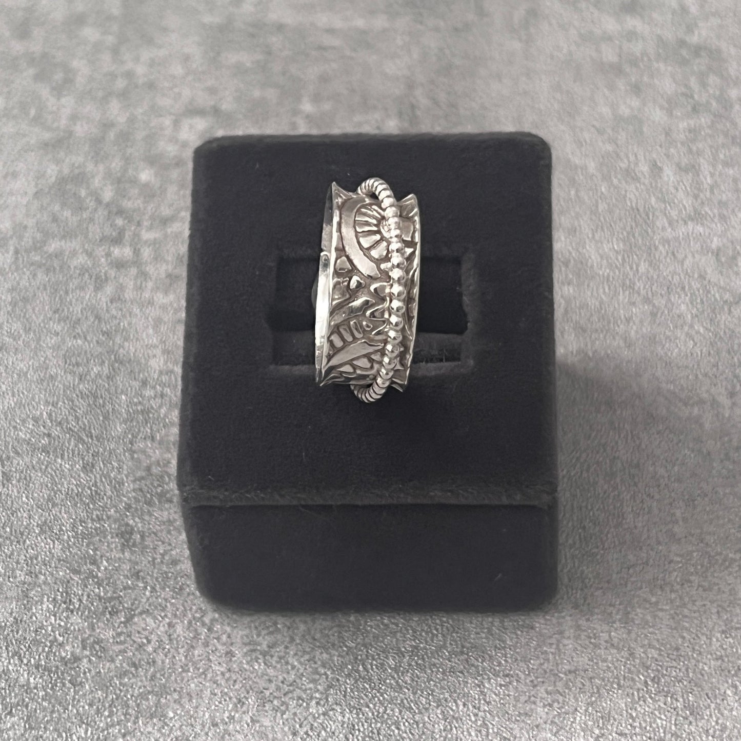 stg silver spinner ring one thick band 8mm wide with an imprinted paisley pattern. Over it spins a silver beaded thin ring 1.5mm wide. The outer ring spins with your touch
