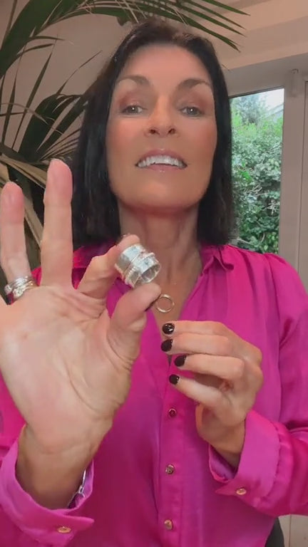 the designer maker is describing the ring wearing a pink blouse black hair