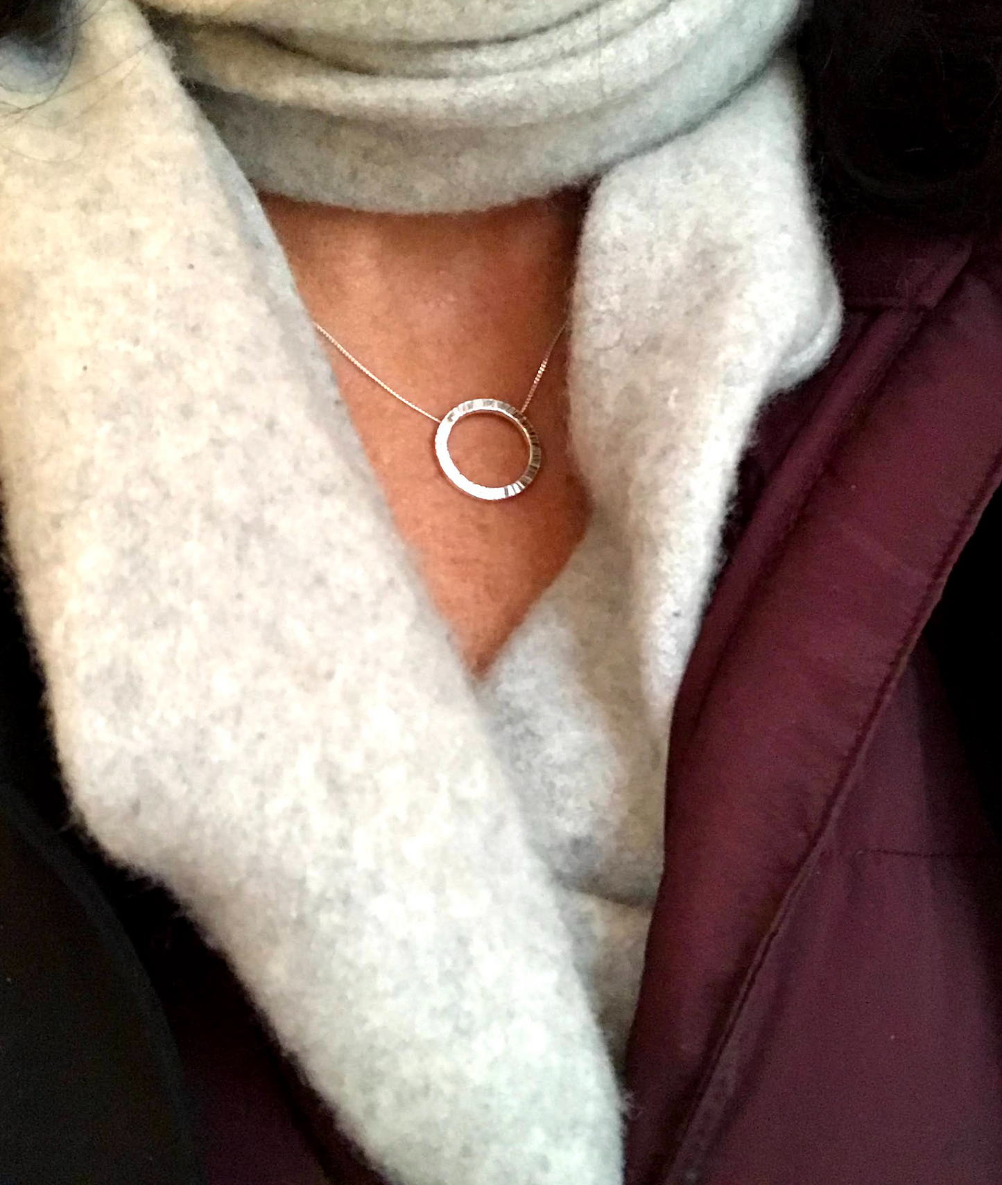 sterling silver circle 19mm with hammer finish like rays of the sun Rise. Model wears a grey cashmere scarf and a wine jacket